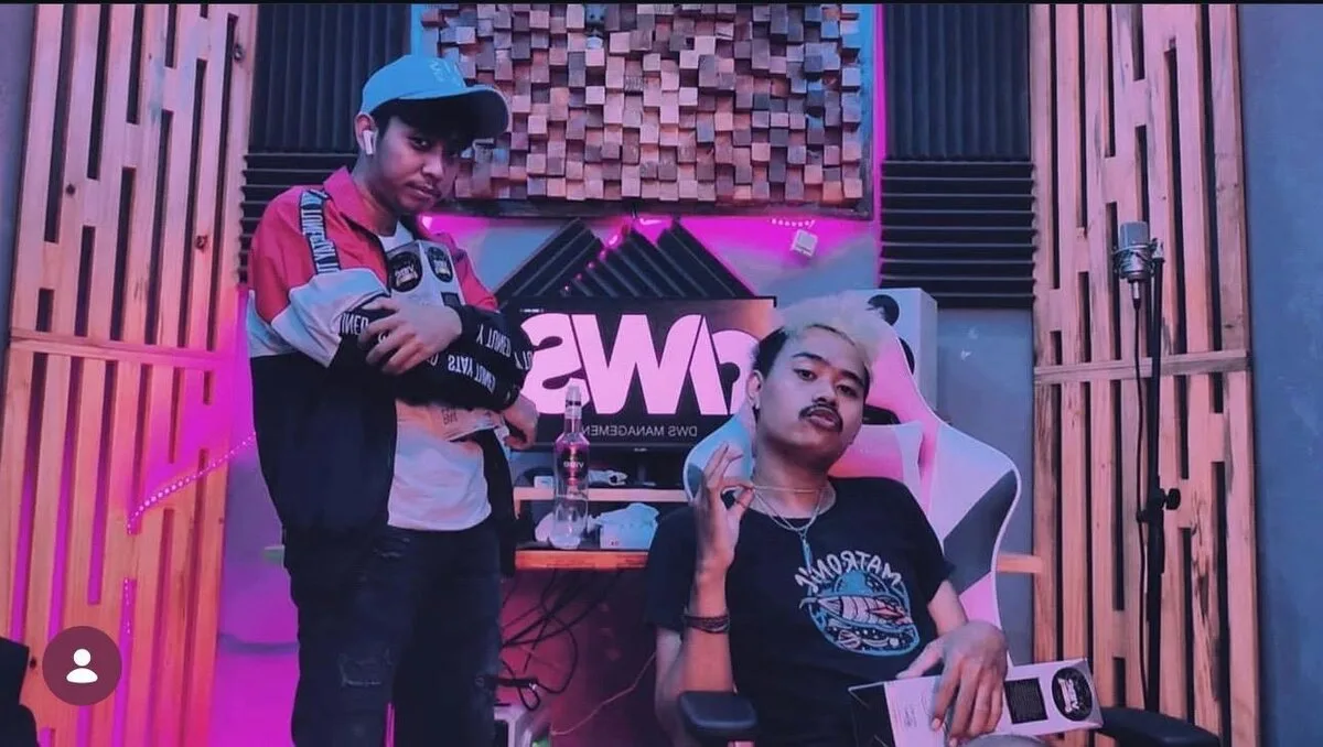Inside the DWS studio with a neon DWS MANAGEMENT sign, acoustic panels and a studio microphone
